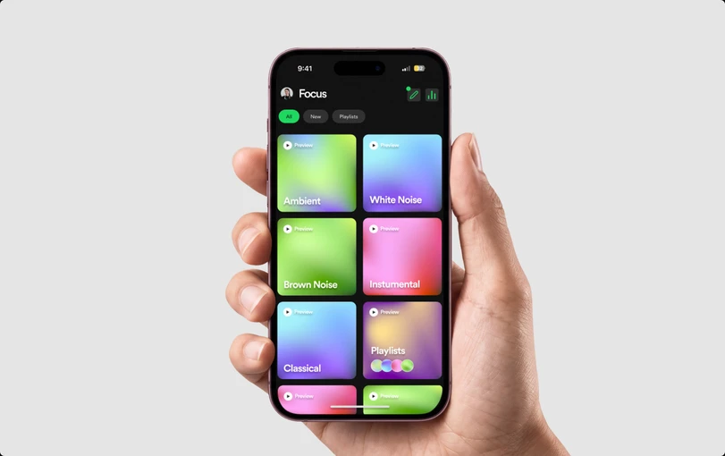 A hand holding a phone showing the Focus home screen with colourful sound tiles